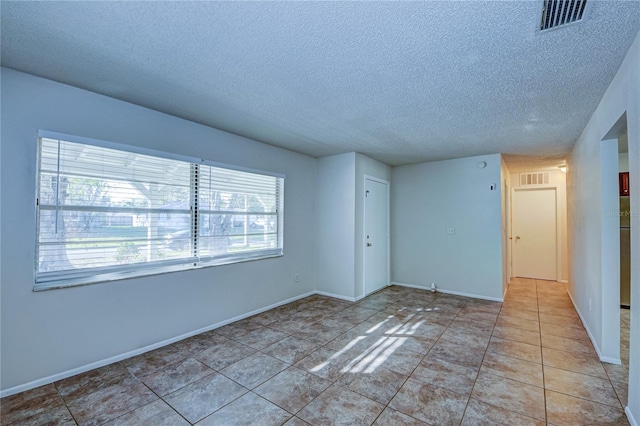 tiled empty room with a textured ceiling