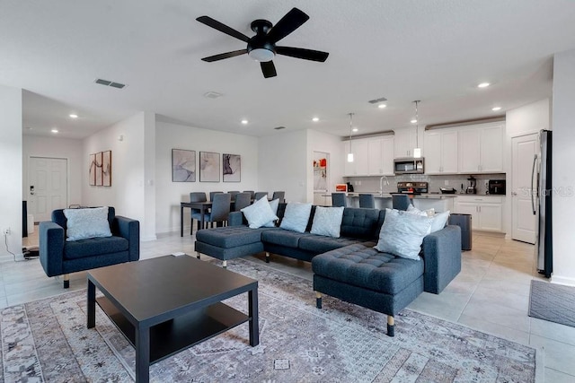 tiled living room with ceiling fan and sink