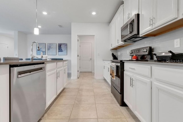 kitchen with backsplash, white cabinets, hanging light fixtures, light tile patterned floors, and appliances with stainless steel finishes