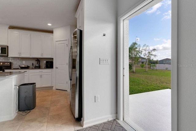 kitchen featuring decorative backsplash, light tile patterned floors, white cabinetry, and appliances with stainless steel finishes