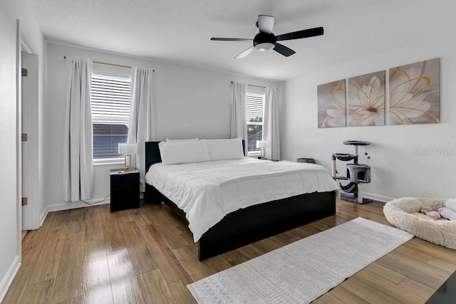 bedroom with multiple windows, hardwood / wood-style floors, and ceiling fan