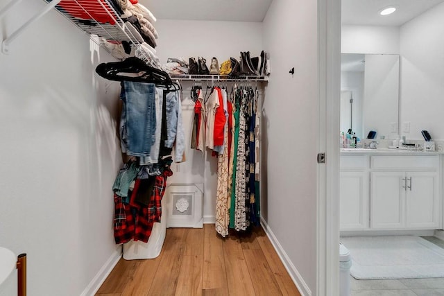 walk in closet with light hardwood / wood-style floors