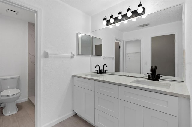 bathroom with vanity, a textured ceiling, and toilet