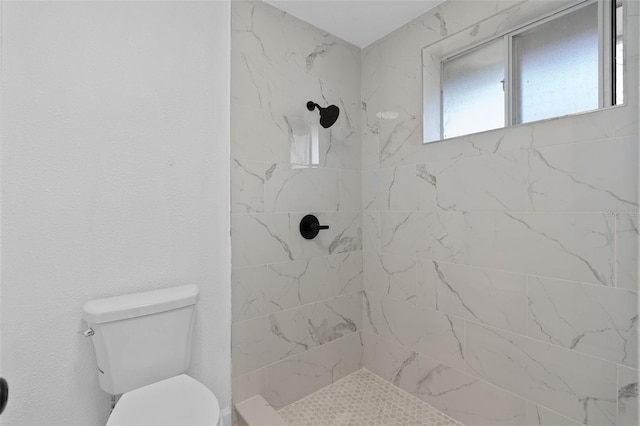 bathroom with a tile shower and toilet