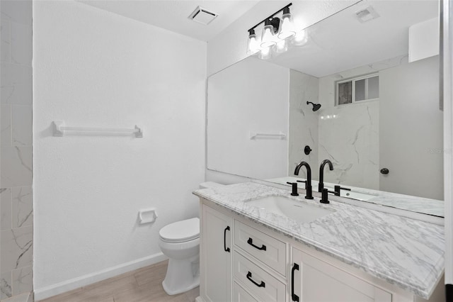 bathroom featuring vanity, toilet, and tiled shower