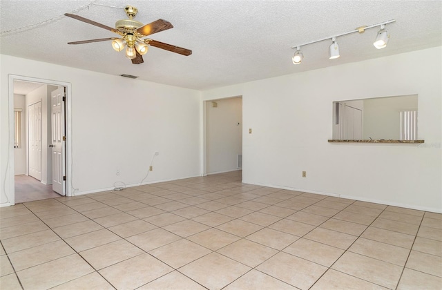 tiled empty room with ceiling fan and a textured ceiling