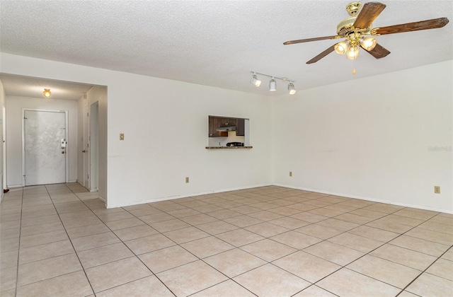 spare room featuring ceiling fan, light tile patterned floors, and a textured ceiling