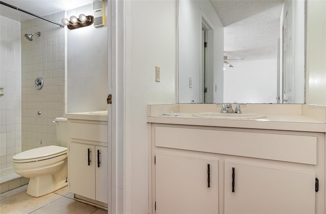 bathroom with a tile shower, ceiling fan, tile patterned flooring, a textured ceiling, and toilet