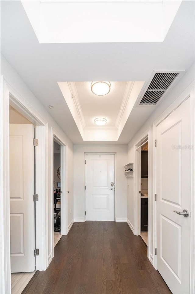 hallway featuring crown molding, dark hardwood / wood-style flooring, and a tray ceiling