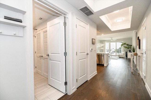 hallway featuring wood-type flooring and a tray ceiling