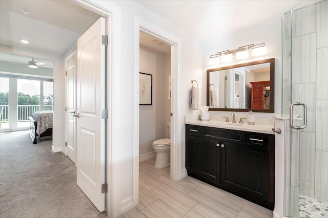 bathroom featuring ceiling fan, toilet, a shower with shower door, and vanity