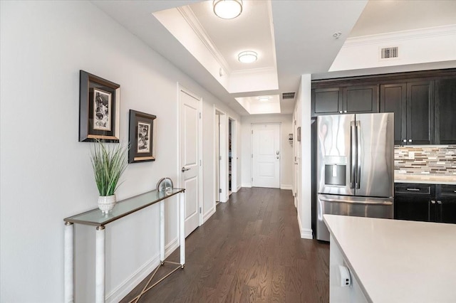 kitchen featuring backsplash, dark hardwood / wood-style flooring, a tray ceiling, ornamental molding, and stainless steel fridge