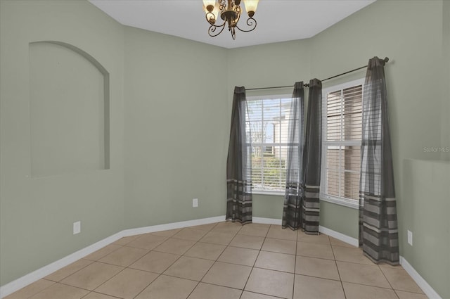 empty room featuring light tile patterned flooring and a chandelier