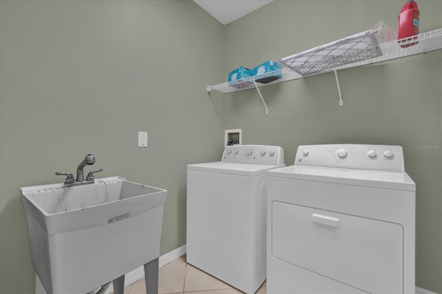 washroom with light tile patterned flooring, washing machine and dryer, and sink