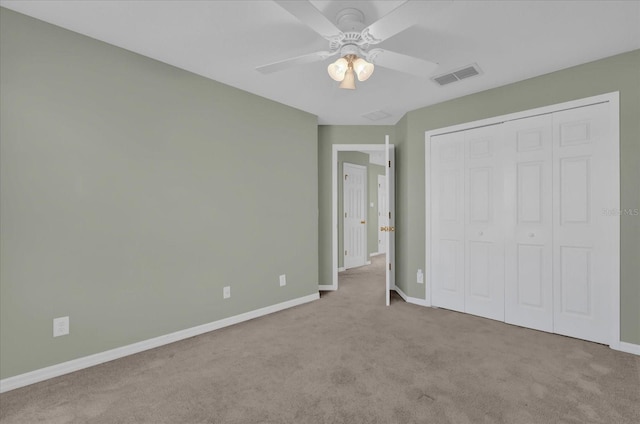 unfurnished bedroom with a closet, light colored carpet, and ceiling fan