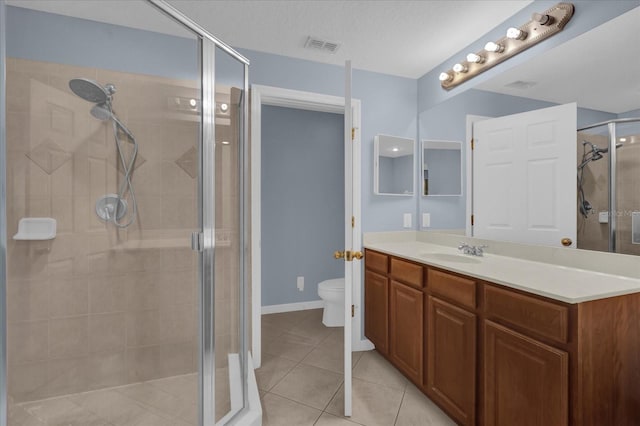 bathroom with tile patterned floors, vanity, toilet, and a shower with door