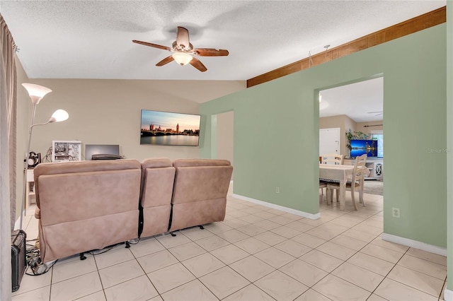 living room featuring ceiling fan, lofted ceiling, a textured ceiling, and light tile patterned floors