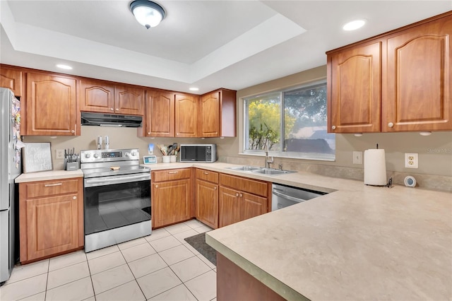 kitchen featuring light tile patterned floors, stainless steel appliances, a tray ceiling, and sink