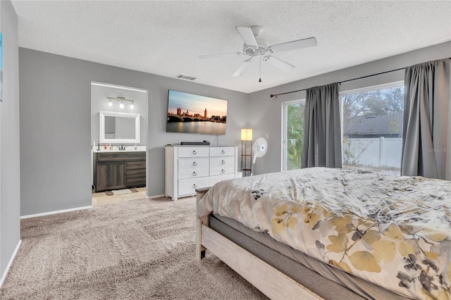 bedroom with ensuite bathroom, sink, ceiling fan, a textured ceiling, and light colored carpet