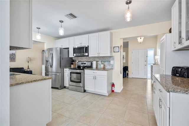 kitchen with white cabinets, light stone countertops, stainless steel appliances, and hanging light fixtures