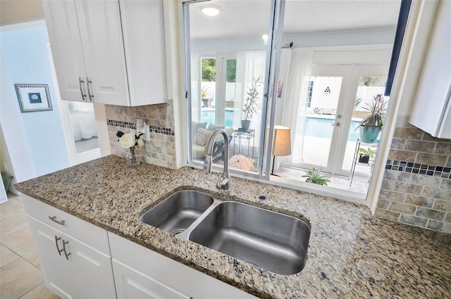 kitchen with stone counters, sink, light tile patterned floors, decorative backsplash, and white cabinets