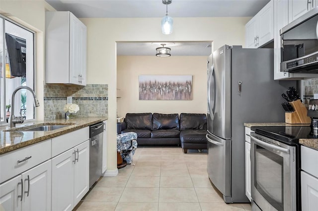 kitchen with light stone countertops, white cabinetry, sink, stainless steel appliances, and tasteful backsplash