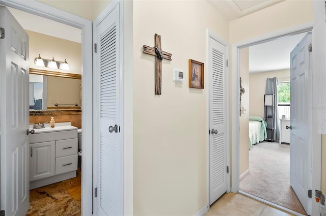 corridor featuring light colored carpet and sink