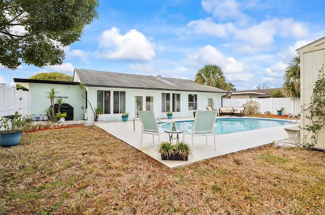 back of property with a fenced in pool, a patio area, and a lawn