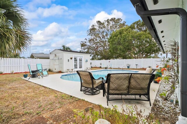 view of swimming pool featuring an outbuilding, a patio, and french doors