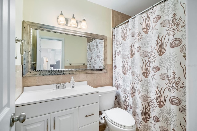 bathroom featuring vanity, toilet, and tile walls