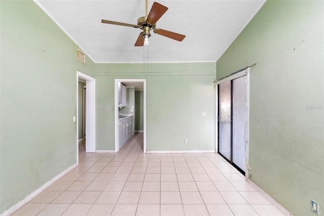 spare room with ceiling fan, light tile patterned flooring, and a textured ceiling