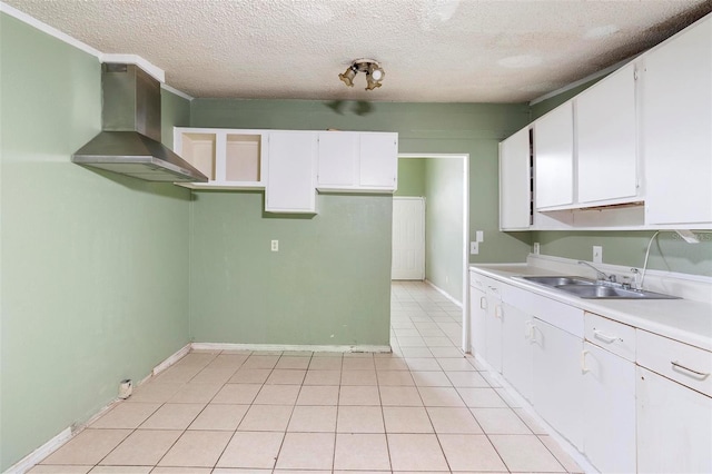 kitchen with a textured ceiling, sink, wall chimney range hood, light tile patterned floors, and white cabinetry