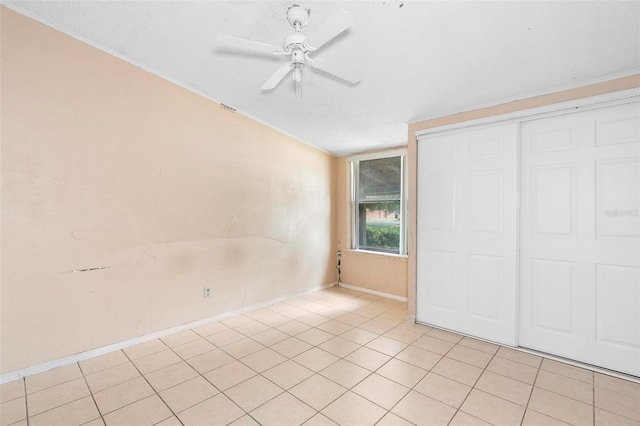 unfurnished bedroom with ceiling fan, light tile patterned flooring, a textured ceiling, and a closet