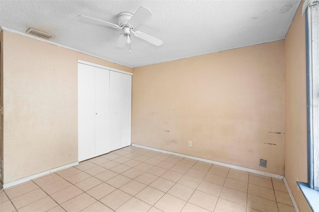 unfurnished bedroom featuring ceiling fan, a closet, light tile patterned flooring, and a textured ceiling