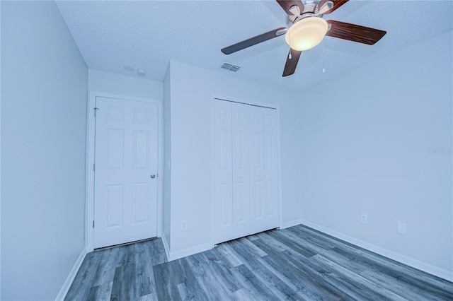 unfurnished bedroom featuring ceiling fan, wood-type flooring, a closet, and a textured ceiling