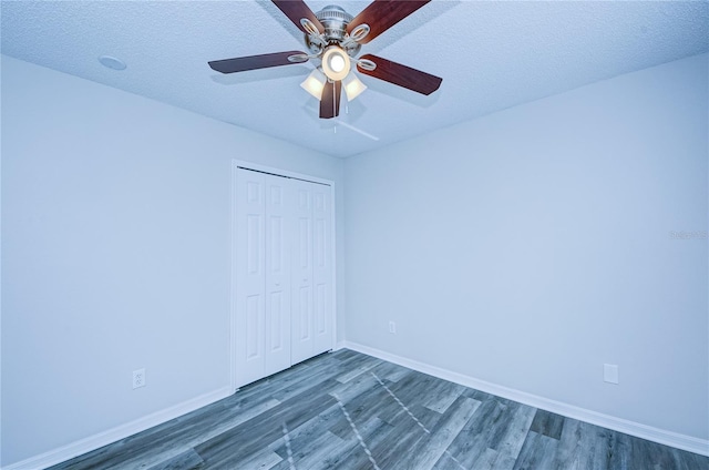 unfurnished bedroom with ceiling fan, dark hardwood / wood-style flooring, a closet, and a textured ceiling