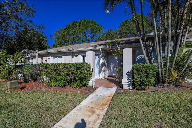 view of front of house with stucco siding and a front lawn