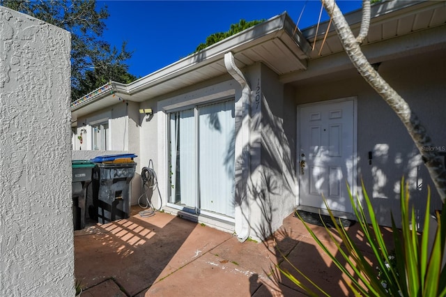 view of exterior entry with a patio and stucco siding