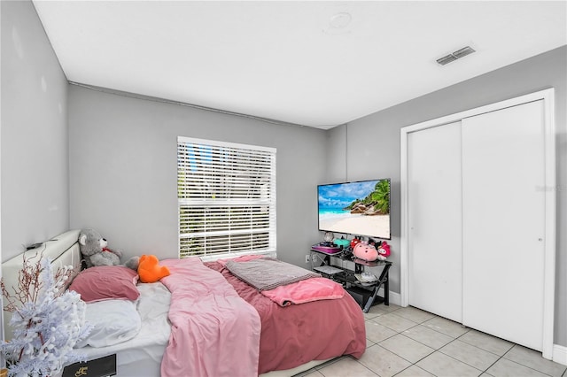 bedroom with light tile patterned floors, visible vents, and a closet