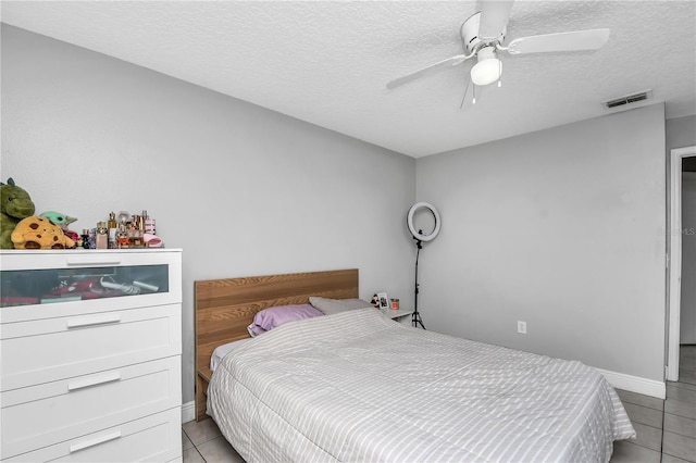 bedroom featuring visible vents, a textured ceiling, light tile patterned flooring, and a ceiling fan