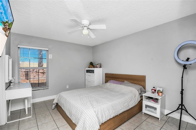 bedroom featuring baseboards, a textured ceiling, light tile patterned flooring, and a ceiling fan