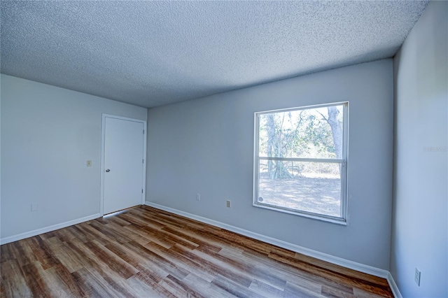 spare room featuring light hardwood / wood-style floors and a textured ceiling