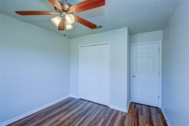 unfurnished bedroom featuring dark wood-type flooring, a textured ceiling, a closet, and ceiling fan