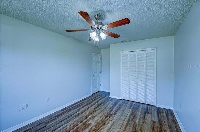 unfurnished bedroom featuring a textured ceiling, a closet, ceiling fan, and dark hardwood / wood-style flooring