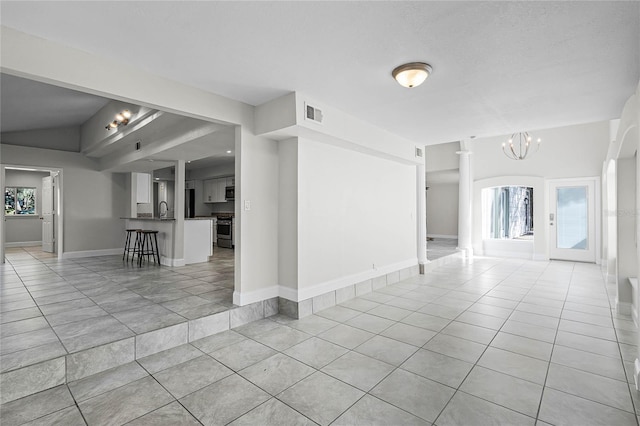 spare room with baseboards, light tile patterned flooring, a notable chandelier, and a sink