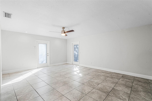 unfurnished room with light tile patterned floors, a ceiling fan, visible vents, and a textured ceiling