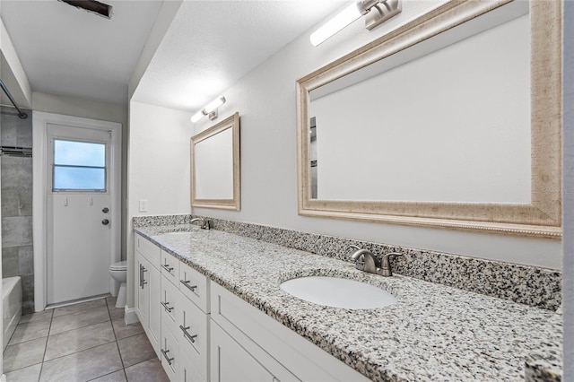 full bath with toilet, double vanity, a sink, and tile patterned floors