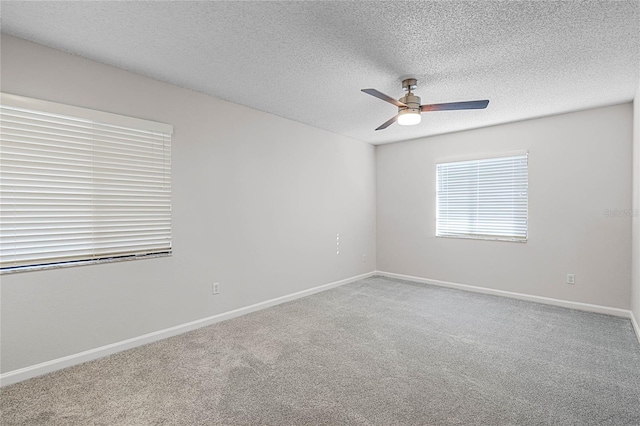 carpeted empty room with a textured ceiling, a ceiling fan, and baseboards