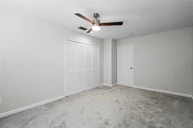 unfurnished bedroom featuring carpet, a closet, visible vents, a textured ceiling, and baseboards