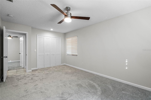 unfurnished bedroom with a textured ceiling, a ceiling fan, baseboards, a closet, and carpet